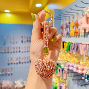 Detail of a sparkling rhinestone heart keychain with a woven strap and gold metal ring