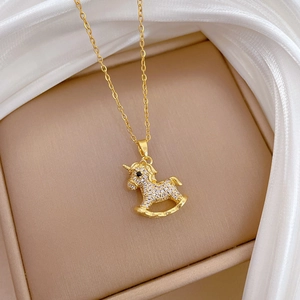 Macro shot of gold rocking horse pendant with white crystal pavé on leather background