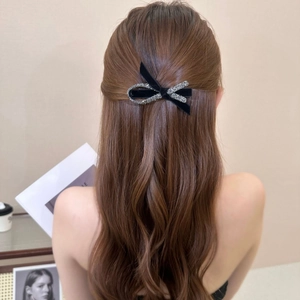 Elegant black velvet bow hair clip with rhinestones worn by a model in a soft indoor setting