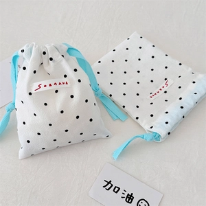 Detail of white drawstring bags with black polka dots and soft blue ribbons