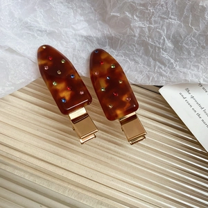 Detailed view of tortoise shell acrylic hair clips with colorful rhinestones on gold base