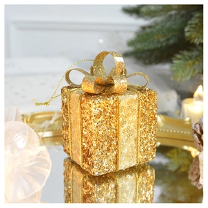 Macro shot of a golden sequin gift box ornament with glitter ribbon for Christmas decor
