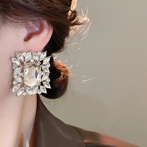 Close-up of square silver stud earring with emerald-cut crystal and marquise rhinestones