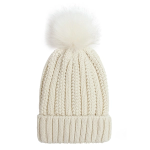 Close-up of cream knit beanie featuring a large faux fur pompom and ribbed texture