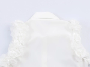Detail of white sleeveless shirt featuring delicate 3D rose applique and classic collar