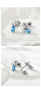 Detail view of starfish shell earring with blue zircon and pearl on white silk fabric