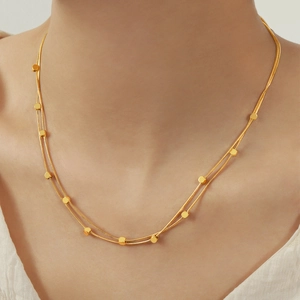 Collier double rang en acier titane doré avec perles carrées porté par un mannequin