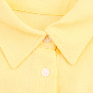 Macro view of yellow linen shirt collar and placket showing fabric texture and buttons