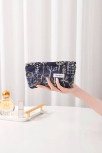 Detail view of navy blue linen pouch with floral embroidery and branded woven label