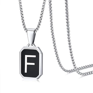 Detail of silver necklace with black octagonal pendant featuring the white letter F