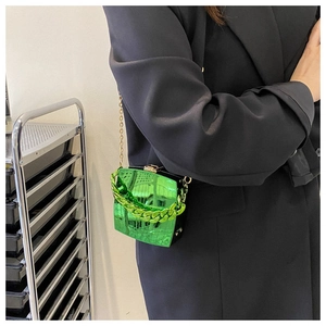 Detail of neon green mirror finish mini bag with chunky chain handle and gold shoulder strap