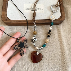Close-up of bohemian heart pendant and leopard floral charm necklaces on rustic fabric