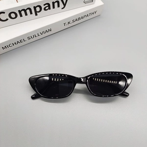 Vue détaillée de lunettes de soleil œil de chat rétro noires avec monture fine sur gris