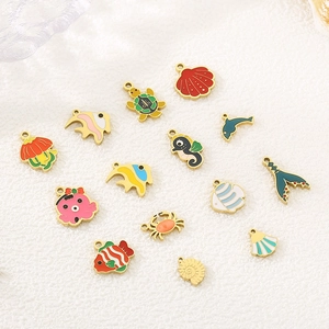 Collection of 15 ocean-themed enamel metal charms with fish, turtles, and shells on fabric