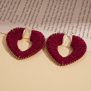 Detail of red knitted heart earrings with gold beads on vintage book pages