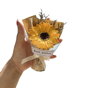 Handmade sunflower bouquet with dry flower accents in brown paper gift wrap on white backdrop