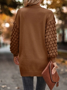 Detail of brown knit cardigan featuring unique scale-textured crochet sleeves in street setting