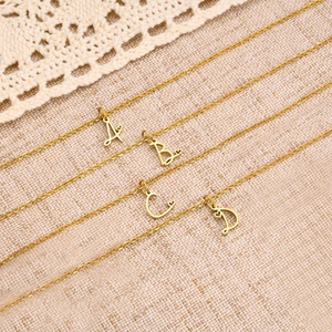 Golden stainless steel necklace featuring cursive alphabet pendants with heart details