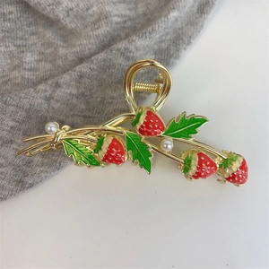 Detail of golden tulip strawberry hair claw with red enamel finish and white pearls