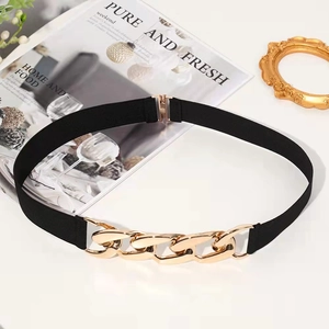Detail of elegant black elastic waist belt with large polished gold metal chain buckle