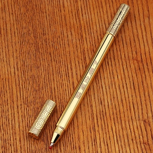 Detailed close-up of golden brass pen featuring traditional bamboo style engravings