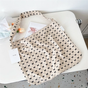 Close-up of beige canvas shoulder bag with black bow patterns and MISS brand tag