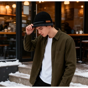 Detailed view of black cable knit beanie with leather logo patch and grey accent stripes