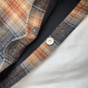 Close-up of the orange plaid wool fabric with metallic magnetic snaps on the bag