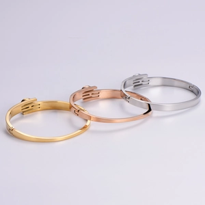 Detailed view of polished H-buckle metal bangles in gold, rose gold and silver finishes