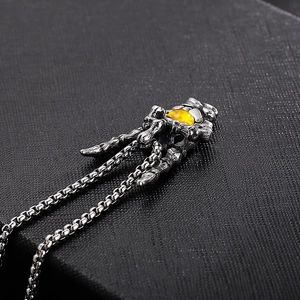 Macro shot of retro silver skeleton hand pendant with yellow tiger eye stone inlay