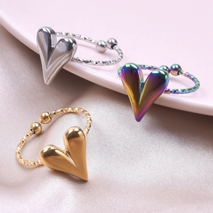 Close-up of fluid heart rings in silver, gold and rainbow finish on pink silk