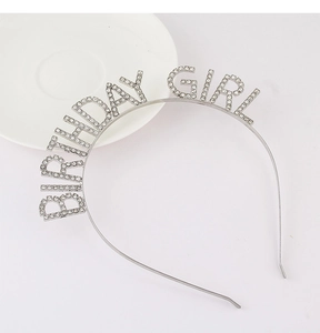 Close-up of a silver Birthday Girl headband with sparkling rhinestones on a white plate