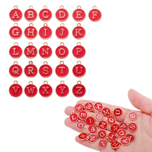 Macro view of 26 round red enamel A-Z alphabet charms in hand for size reference