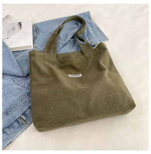 Detail of army green canvas tote bag with fashion label and styling accessories