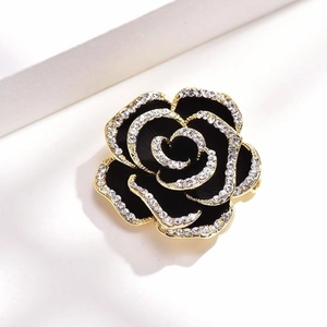 Elegant black rose brooch with gold edges and crystals on minimalist background