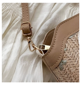 Détail de la bandoulière en cuir avec crochet doré sur sac seau en paille tressée