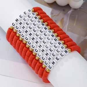 Macro detail of red polymer clay CHEER bracelets with golden beads on display