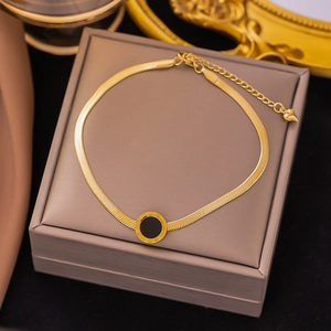 Detailed macro view of gold-plated snake chain anklet with roman numeral disc and heart charm
