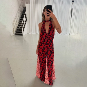 Detail of floral halter jumpsuit with red roses on black and pink panel wide legs