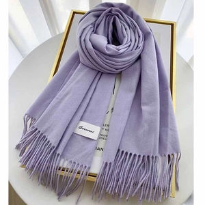 Detailed texture of lavender cashmere scarf with fine fringes and brand tag on frame