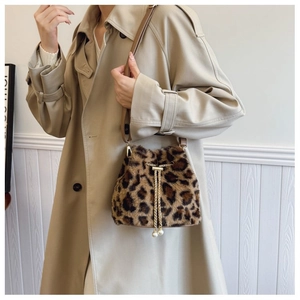 Detail of plush leopard print bucket bag featuring pearl charms and metal chain drawstring