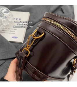 Macro detail of glossy dark brown patent leather and shiny gold metal buckle on bucket bag