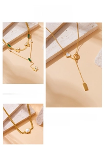 Detail of layered gold-plated necklaces with butterfly, emerald, heart and pearl charms