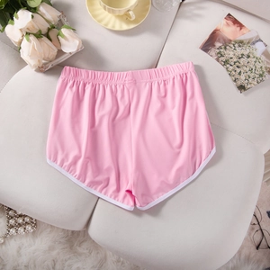 Flat lay of pink women's yoga shorts with white rolled edges on a cozy sofa background