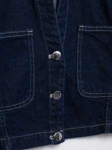 Detailed close-up of dark blue denim shirt jacket with silver buttons and twin pockets