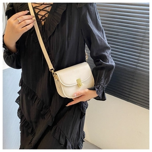 Detailed view of a white leather saddle bag with a golden clasp on a female model