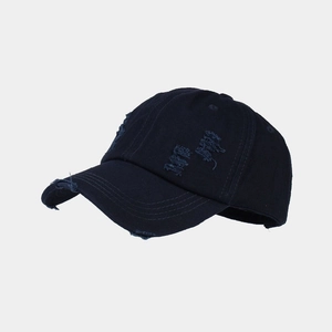 Detailed close-up of distressed navy blue cotton baseball cap with torn fabric details