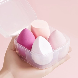 Hand holding transparent case with 4 assorted pink and white makeup sponge blenders