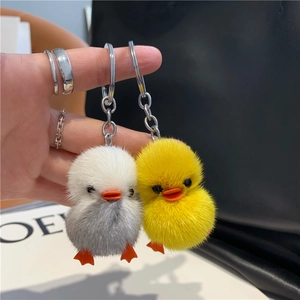 Close-up of cute plush duck keychains in grey and yellow with soft mink fur texture