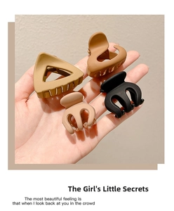 Detail of four matte shark hair clips in earth tones including black and brown